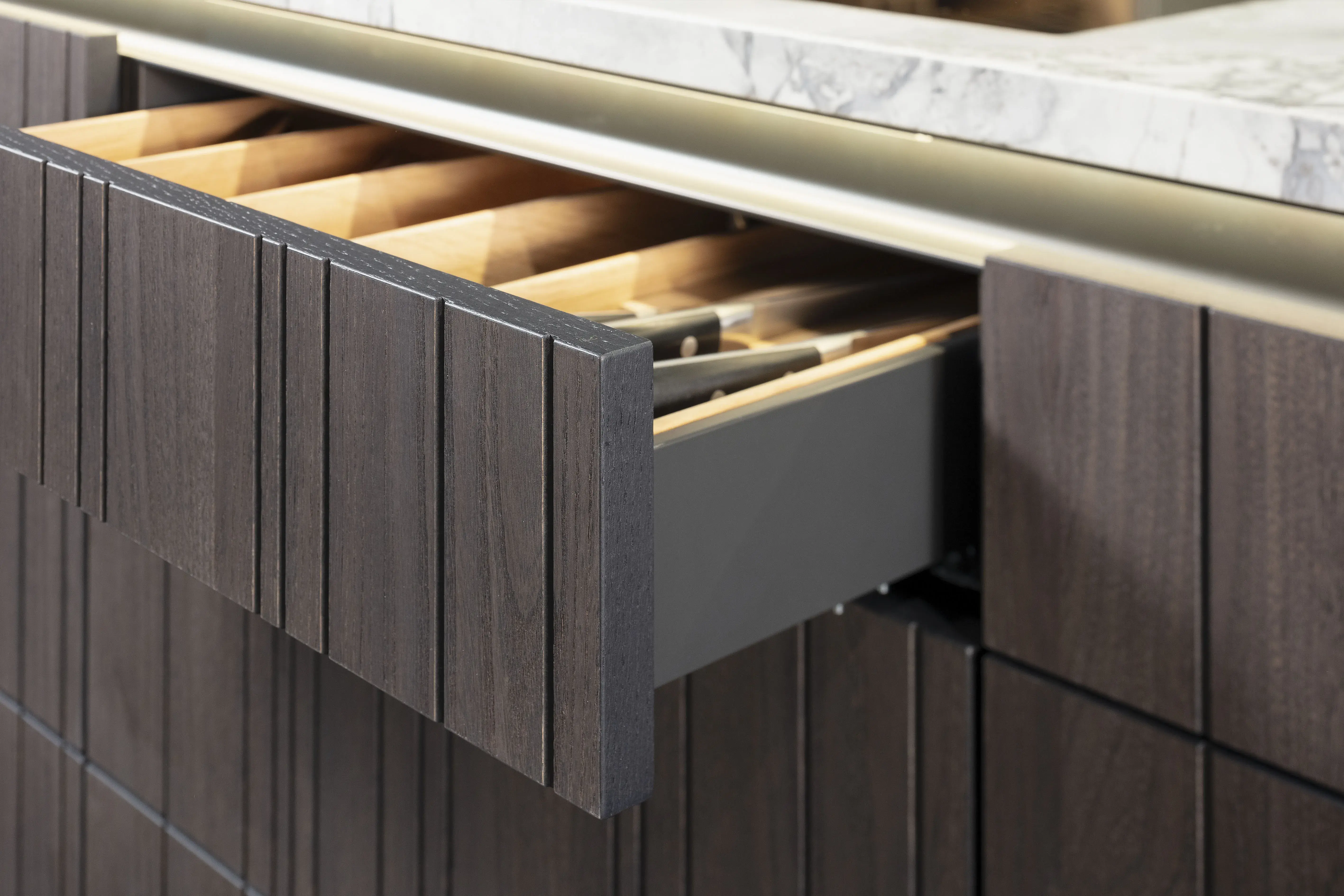 Offene Küchenschublade mit Holzfächern unter einer Marmorarbeitsplatte