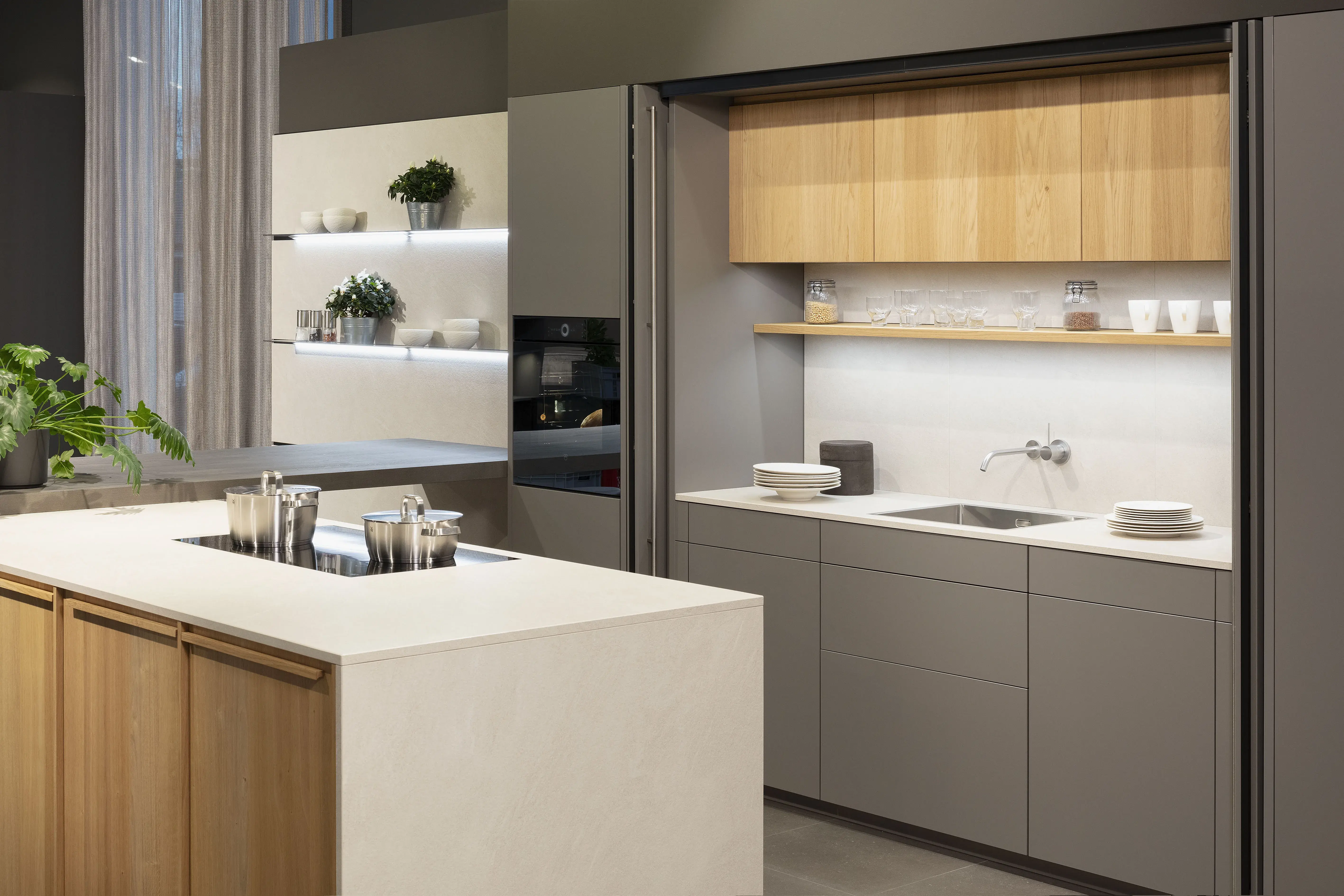 Moderne Küche mit grauen Schränken, Holzdetails und heller Kochinsel.